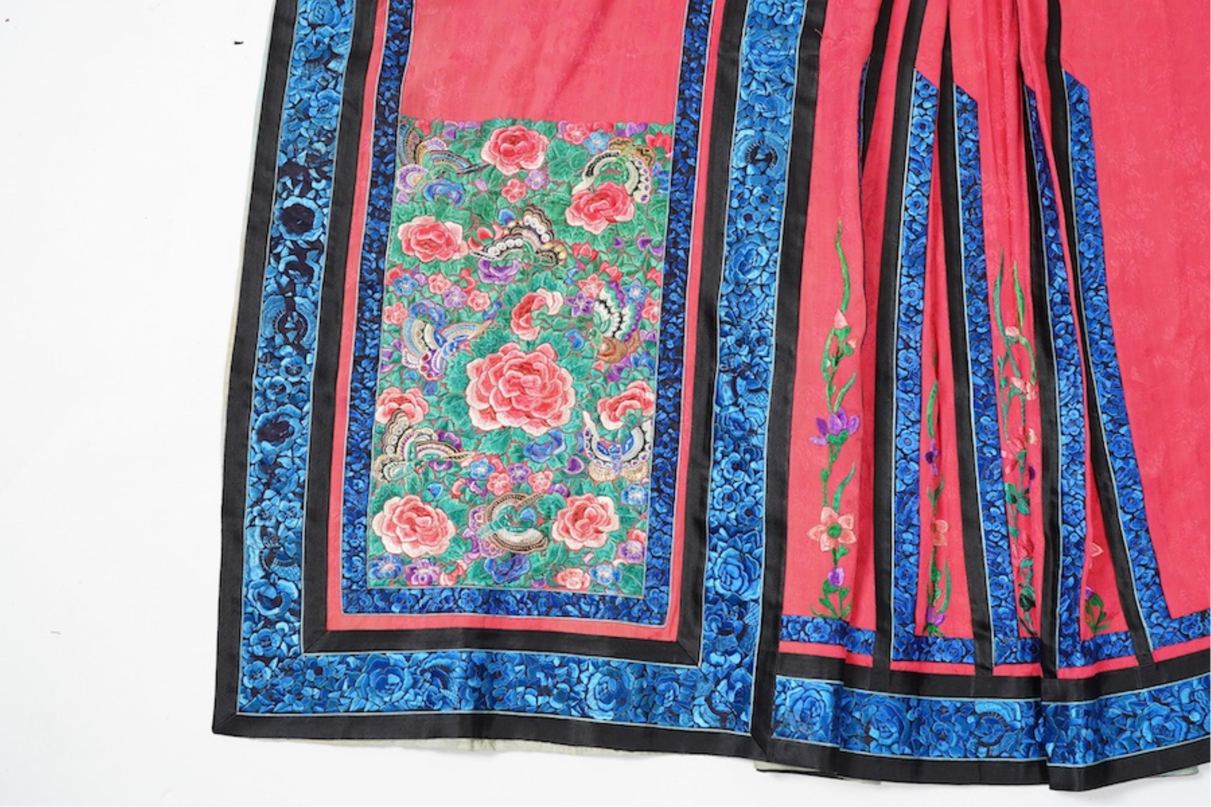 Two late 19th early 20th century Chinese wedding skirts. Made with pink silk damask, embroidered with large decorative silk floral and butterfly front panels bordered by blue embroidered black silk borders between pleats